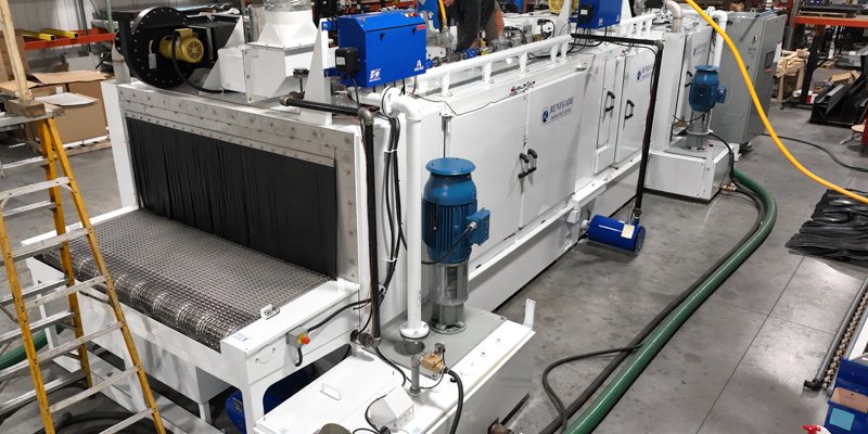 Renegade parts washer machine with industrial conveyor belt and blue control panels.