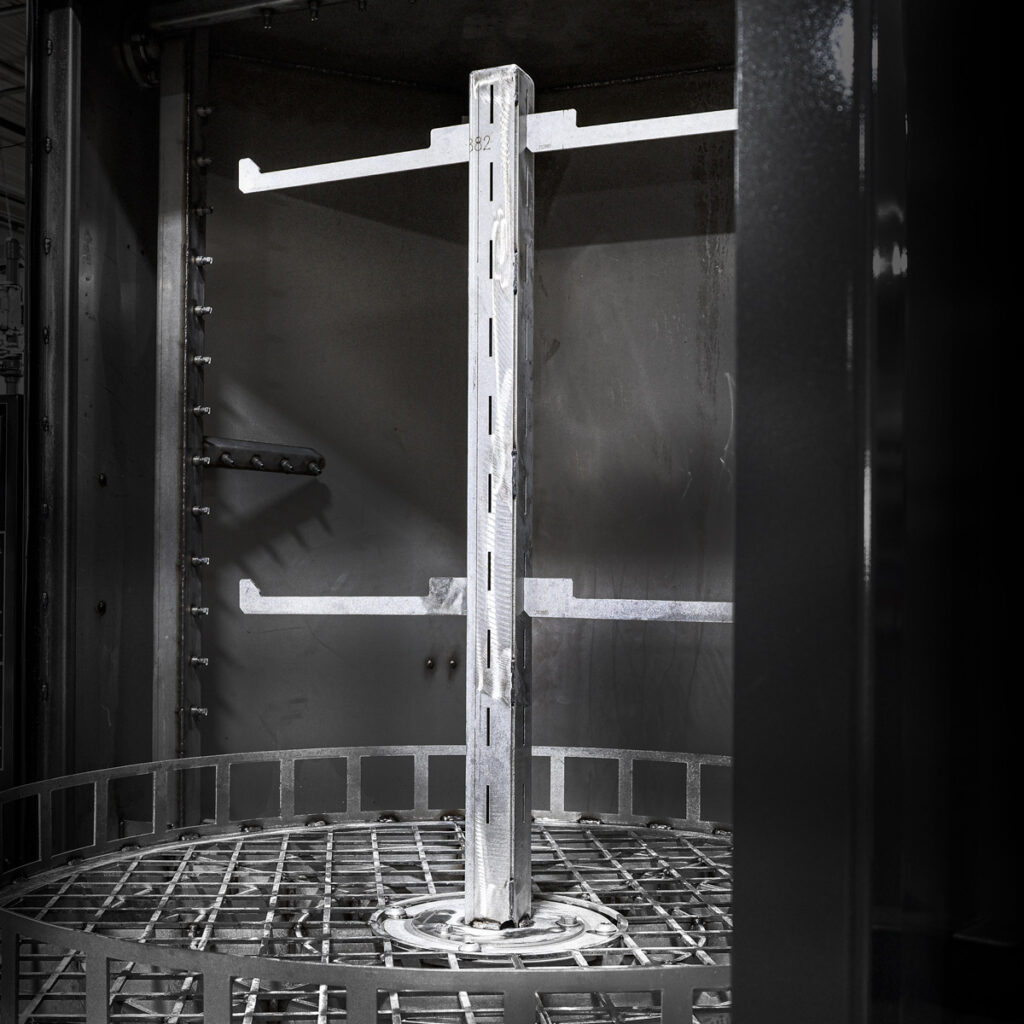 Inside a parts cleaning machine, a central spindle holds racks for cleaning components.